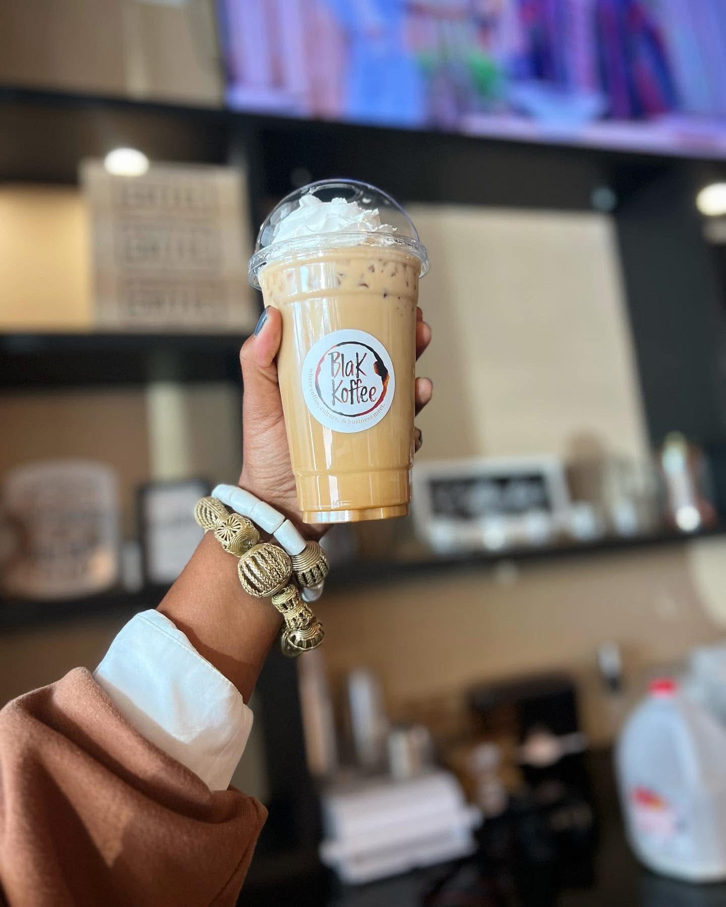 Iced latte with whipped cream held up in the café