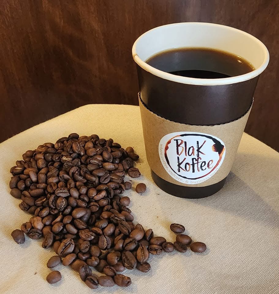 Blak Koffee branded cup with coffee beans spilled beside it